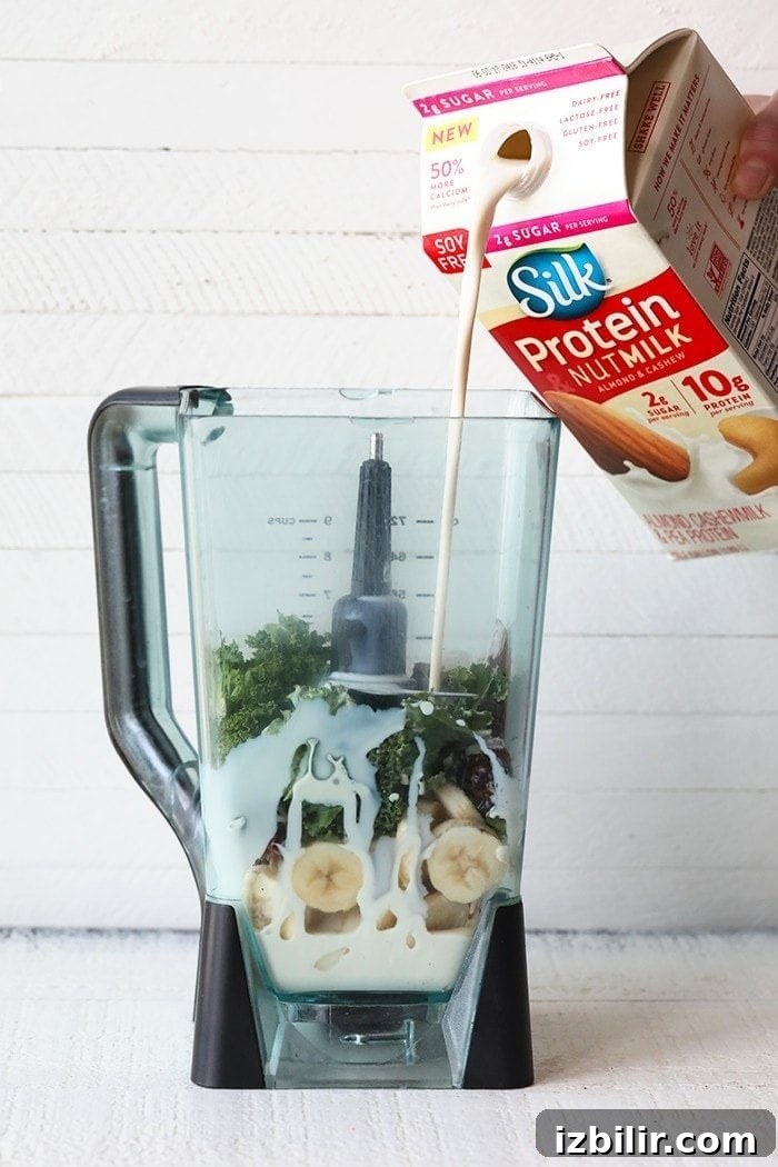 pouring silk nut milk into blender with a banana date smoothie