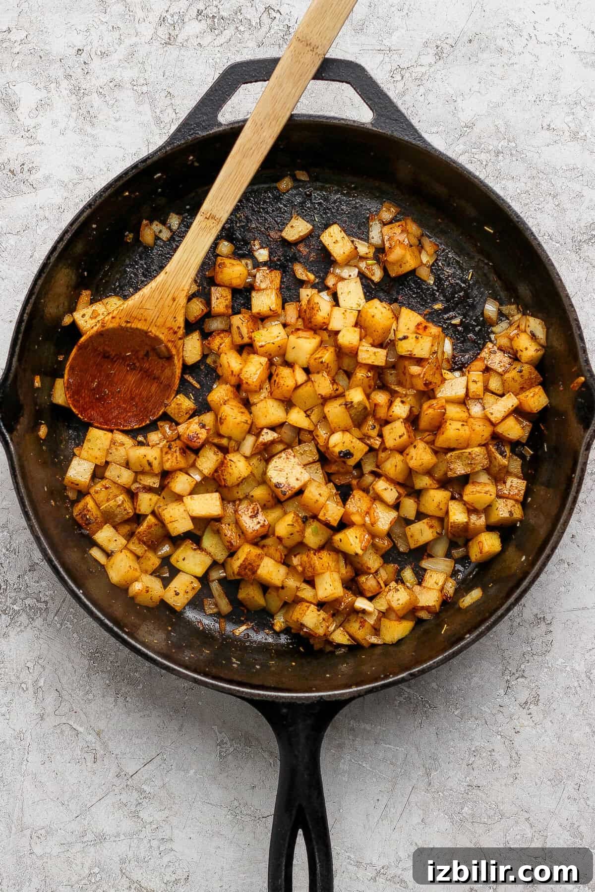 Diced potatoes and onions seasoned and cooked in a cast iron skillet.