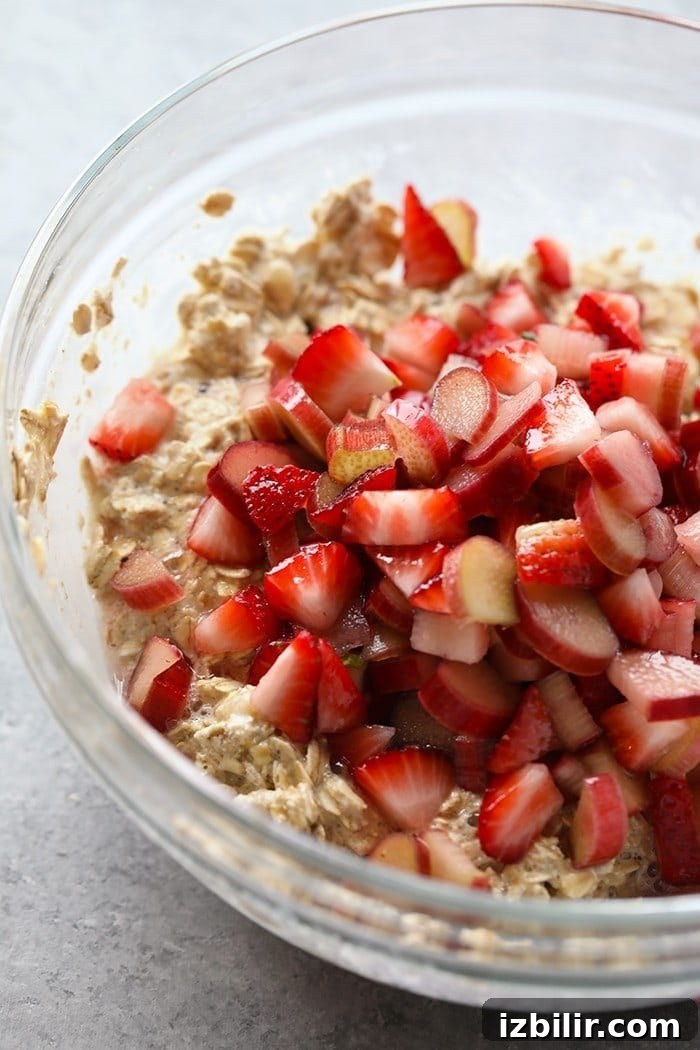 Strawberry Rhubarb Baked Oatmeal Recipe 3 Bowl of sliced strawberries and rhubarb with oatmeal ready to be stirred and placed in a baking dish.