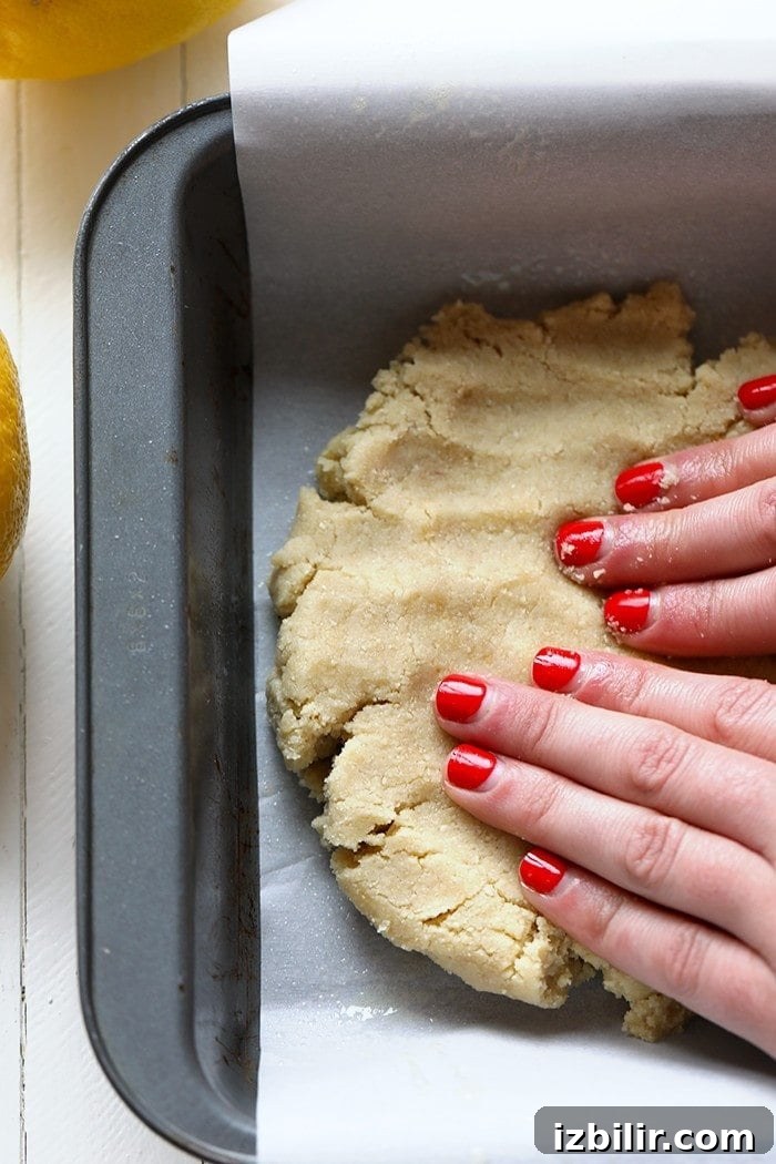 lemon bar crust being pressed in pan.