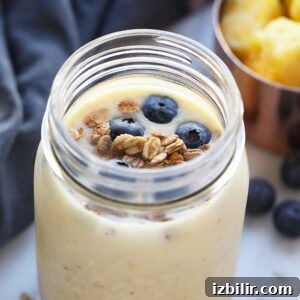 Breakfast in a jar with blueberries and granola, accompanied by a ginger pineapple smoothie.