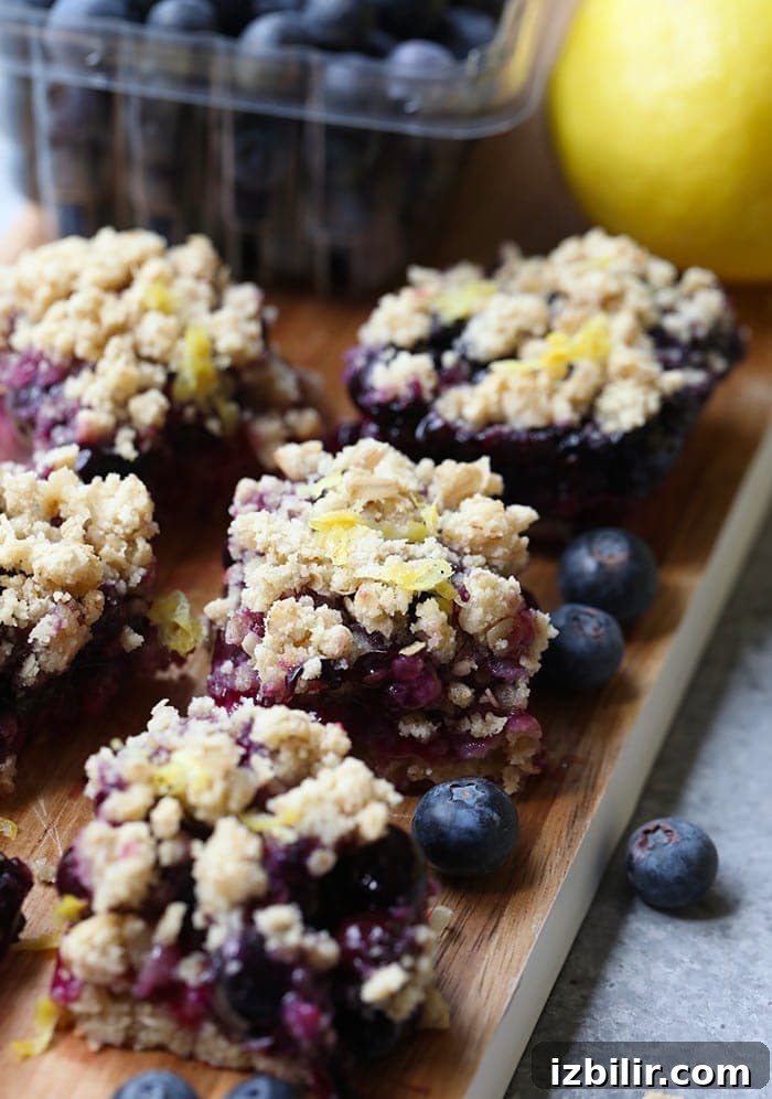 Zesty Lemon Blueberry Crumble Bars with Buttery Oat Crust 2 Lemon blueberry crumble bars on a cutting board.