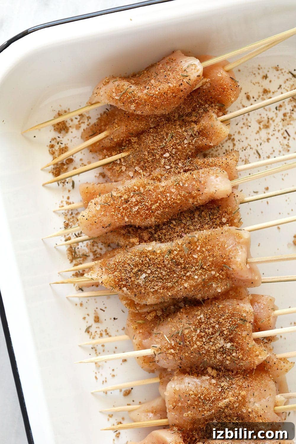 These BBQ Chicken Skewers are the perfect summer meal! Grab some skewers, BBQ sauce, and your favorite BBQ side dish and let's grill! Raw chicken with spices on them.