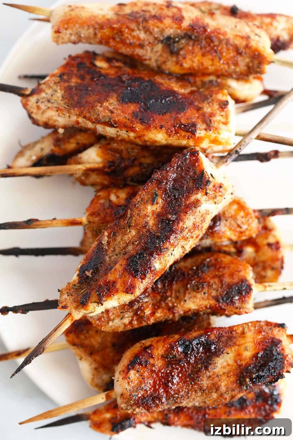These BBQ Chicken Skewers are the perfect summer meal! Grab some skewers, BBQ sauce, and your favorite BBQ side dish and let's grill! Grilled chicken skewers on a plate.