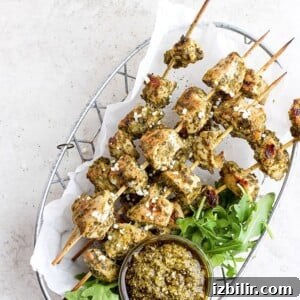 Grilled BBQ Chicken Skewers with Tangy Glaze 2 chicken skewers with pesto on a plate.