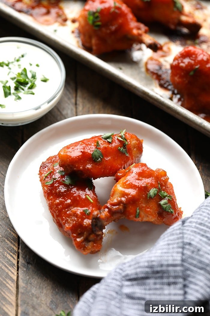 Make any game day or fun family gathering extra tasty with these Healthy Baked Chicken Wings. 3 baked buffalo chicken wings on white plate