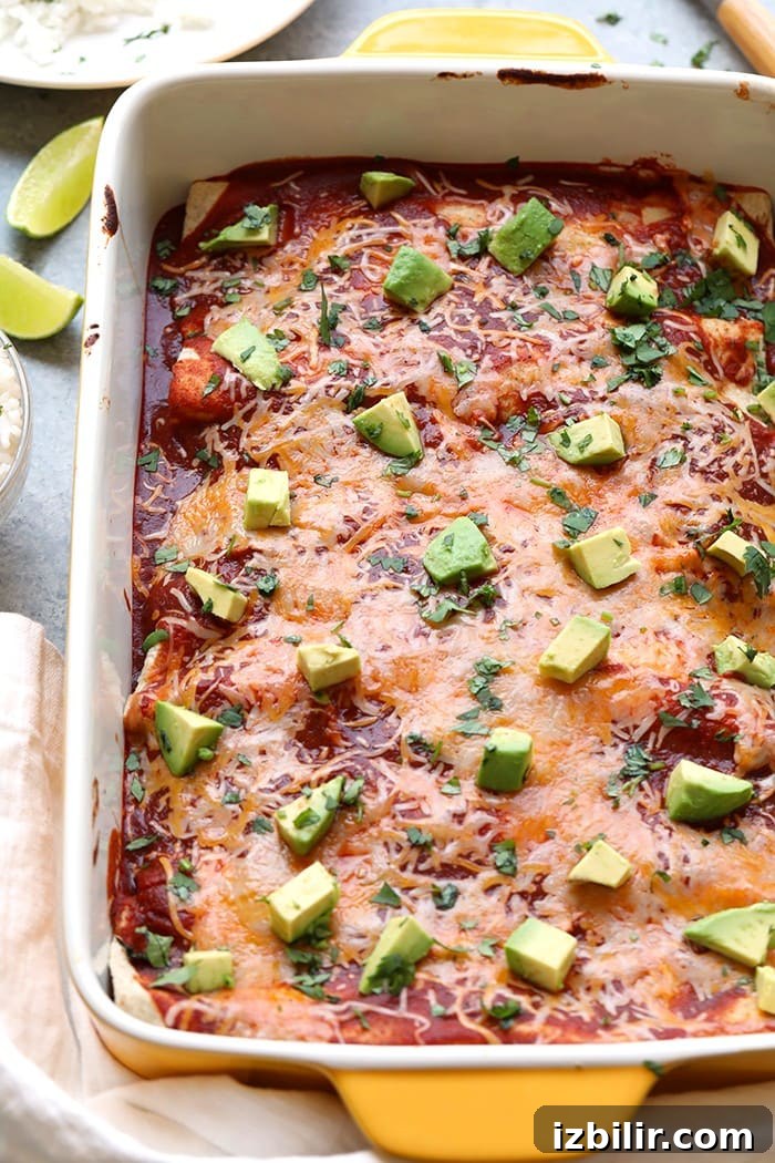 baking dish full of healthy chicken enchiladas topped with melted cheese and avocado