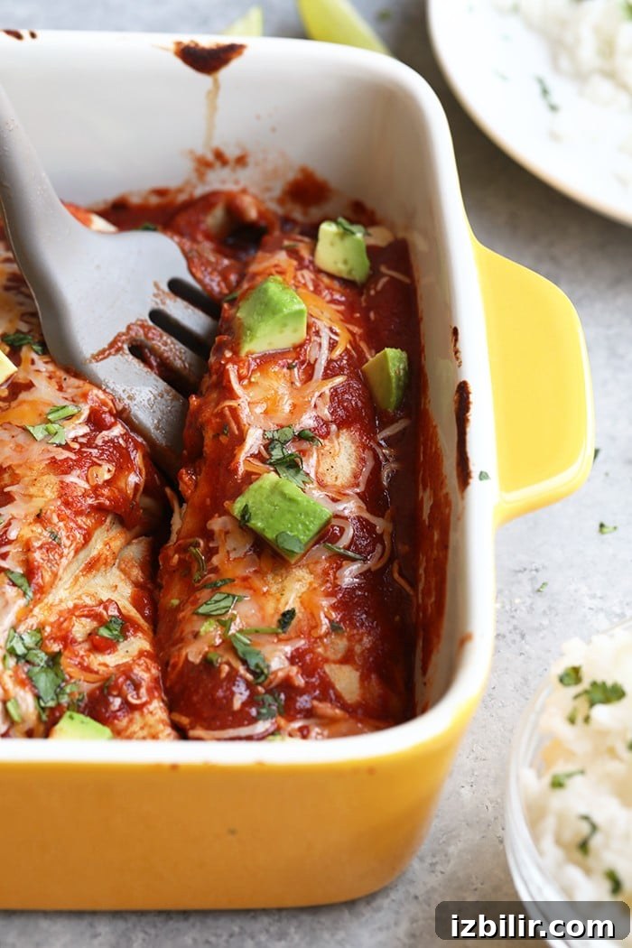 spatula dishing out a healthy enchilada from yellow baking dish