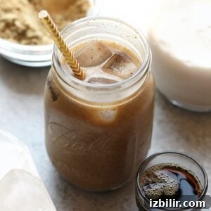 a protein drink in a mason jar filled with cold brew coffee and a straw.