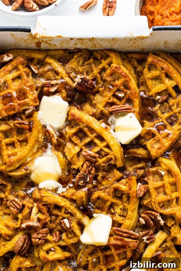 Pumpkin waffles in a baking dish with butter and pecans.
