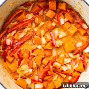 Creamy Thai Coconut Curry Soup with Lime and Ginger 10 A pot filled with sweet potatoes and red peppers.