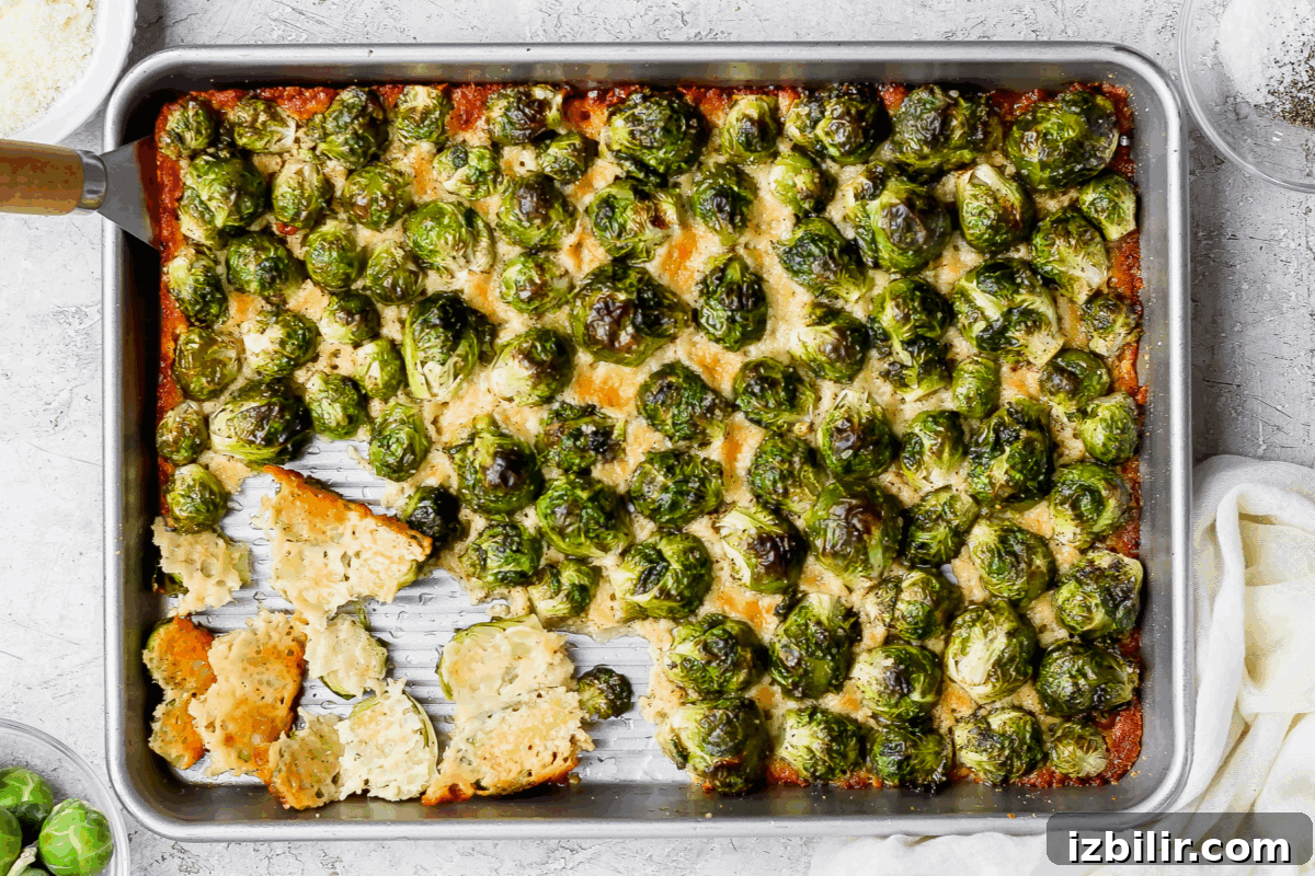Crispy Parmesan-Crusted Brussels Sprouts Recipe 2 Sheet pan of parmesan crusted Brussels sprouts topped with melted cheese, with several crispy cheese crisps at the corner of the pan.