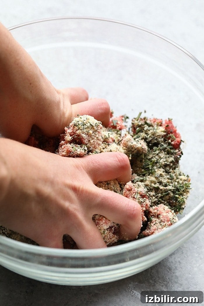 Mixing meatballs in a large glass bowl Mixing meatballs in a large glass bowl