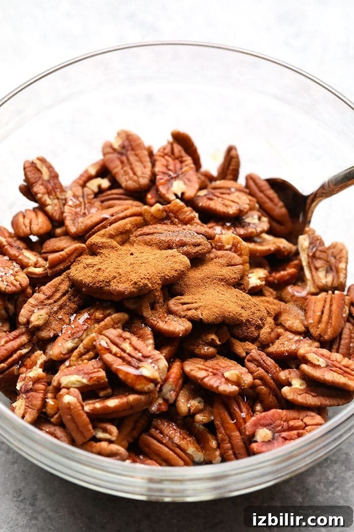 Maple Roasted Pecans Maple roasted pecans with cinnamon in a mixing bowl.