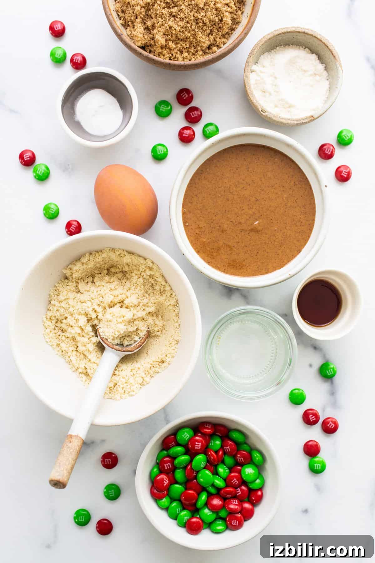 Christmas cookie ingredients on a white marble table.
