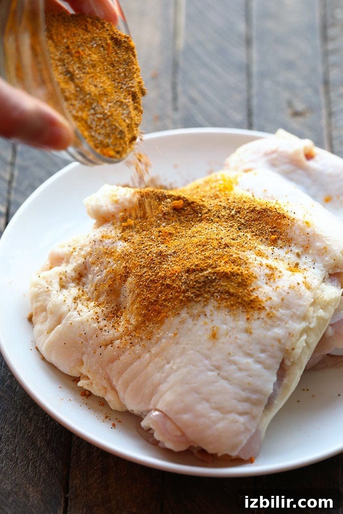 Pouring dry rub onto chicken thighs