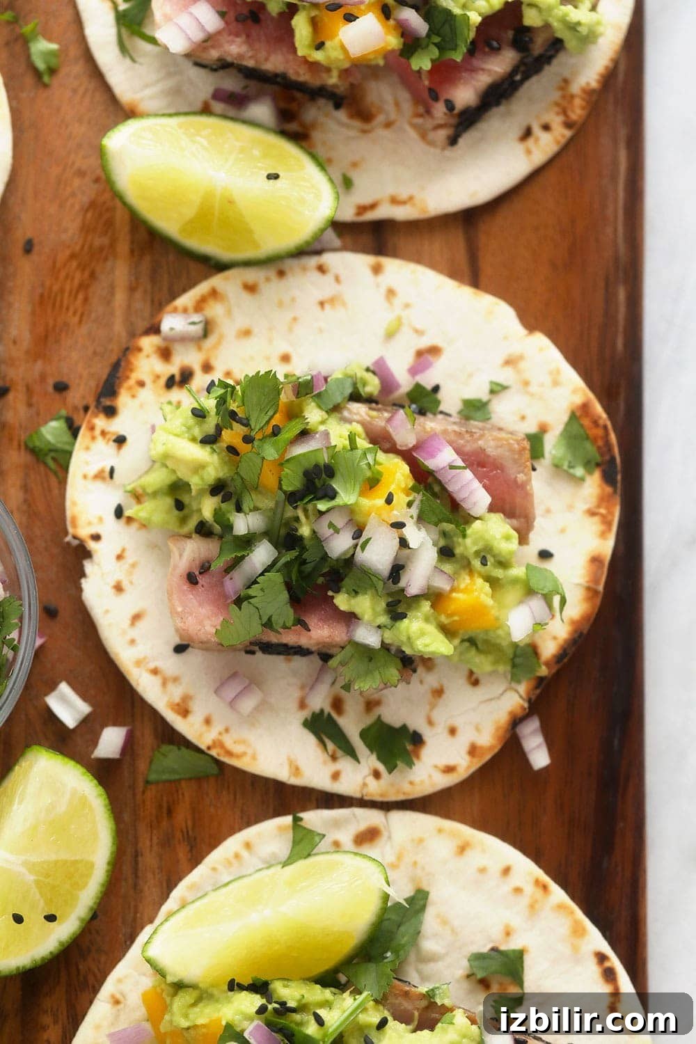Ahi tuna tacos seared with sesame seeds and served with mango guacamole Ahi tuna tacos on cutting board