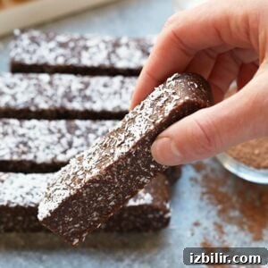 No-Bake Chocolate Coconut Energy Bars Recipe 6 A person dipping a chocolate coconut bar