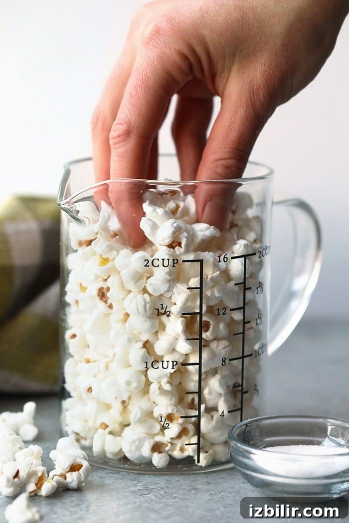 hand reaching for popcorn in glass