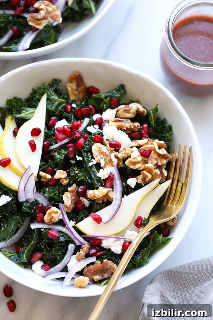 Make this kale pomegranate salad with fresh pears, walnuts, pomegranate arils, and the most delicious homemade pomegranate salad dressing! kale salad in bowl