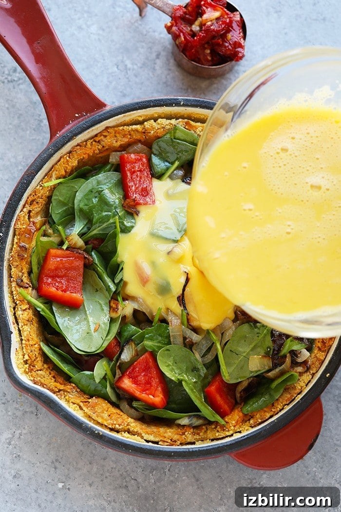 This sweet potato crust quiche has the most amazing crust that's made with sweet potatoes and almond flour. The quiche is packed with eggs, veggies, and goat cheese. spinach, peppers, and onions in pan