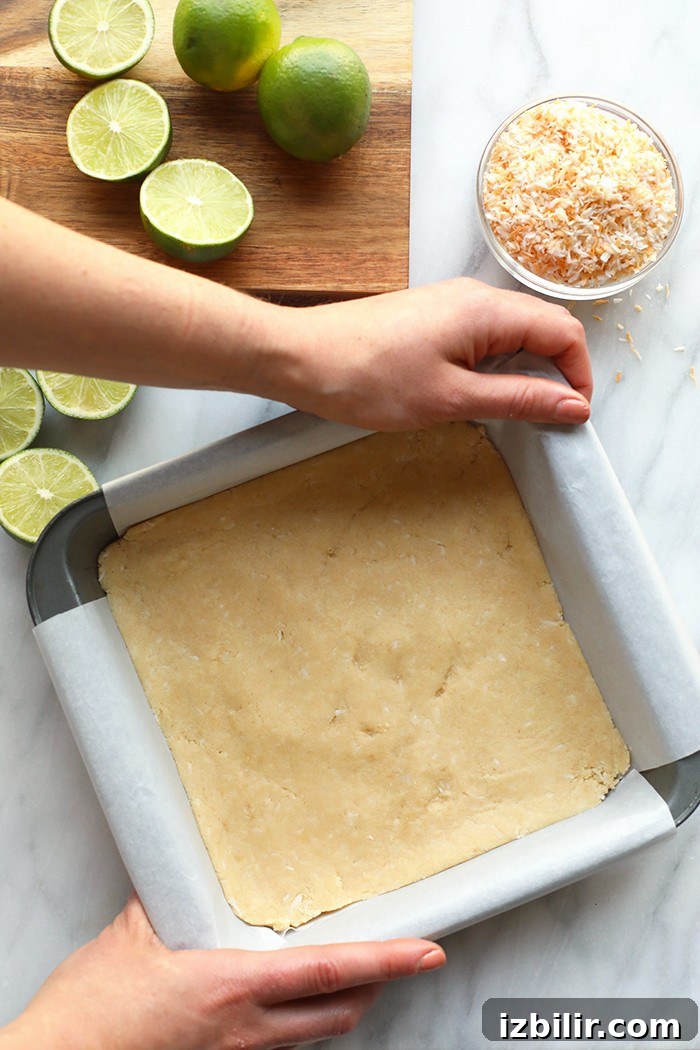Coconut key lime pie bars have a delicious crust made of almond flour and coconut. coconut pie bar crust in a pan