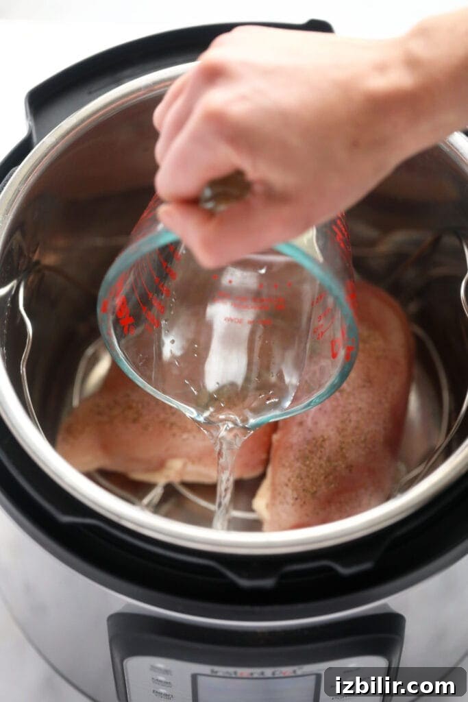 water being poured in the instant pot for instant pot shredded chicken.