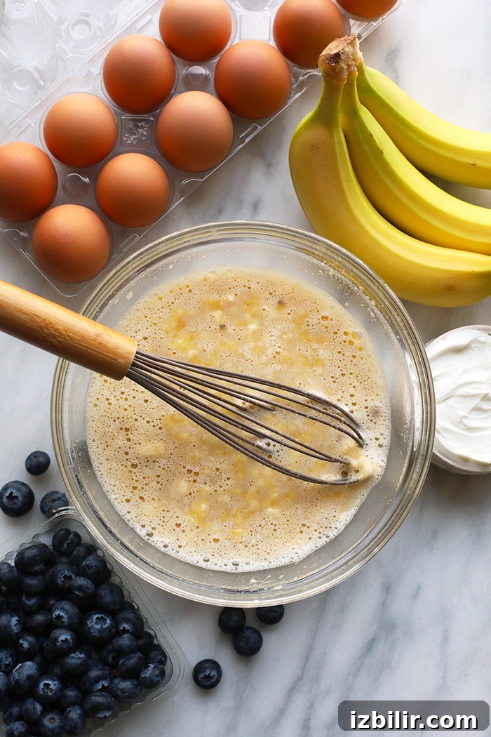 These healthy blueberry muffins are sweetened with honey and bananas and are moistened with greek yogurt! A mixing bowl with all wet ingredients