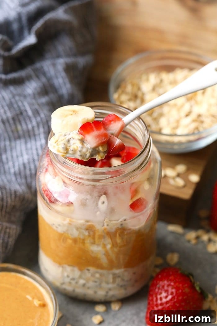Vegan overnight oats topped with strawberries and bananas on a spoon.