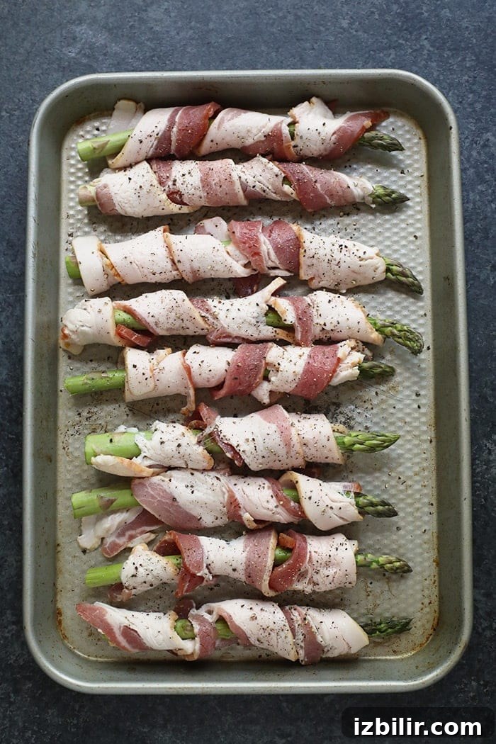 Bacon Wrapped Asparagus is delicious, easy to make, and perfect for a weeknight side dish! Bacon wrapped asparagus on a baking sheet