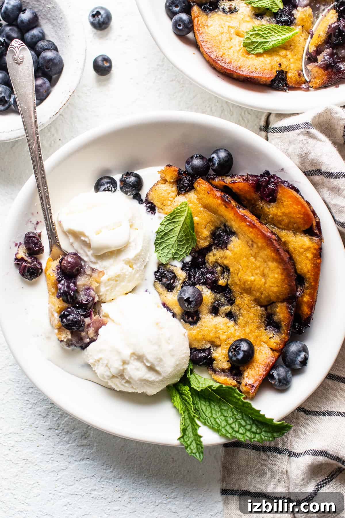 This stunning blueberry cobbler is made with bursting blueberries and a simple cobbler topping for a perfect summer treat. blueberry cobbler with ice cream in bowl.