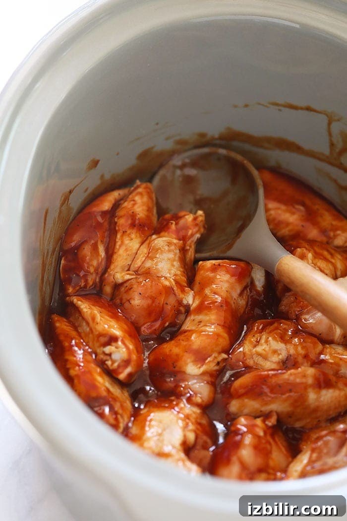 Chicken wings simmering in BBQ sauce in a crockpot chicken wings in sauce in crockpot