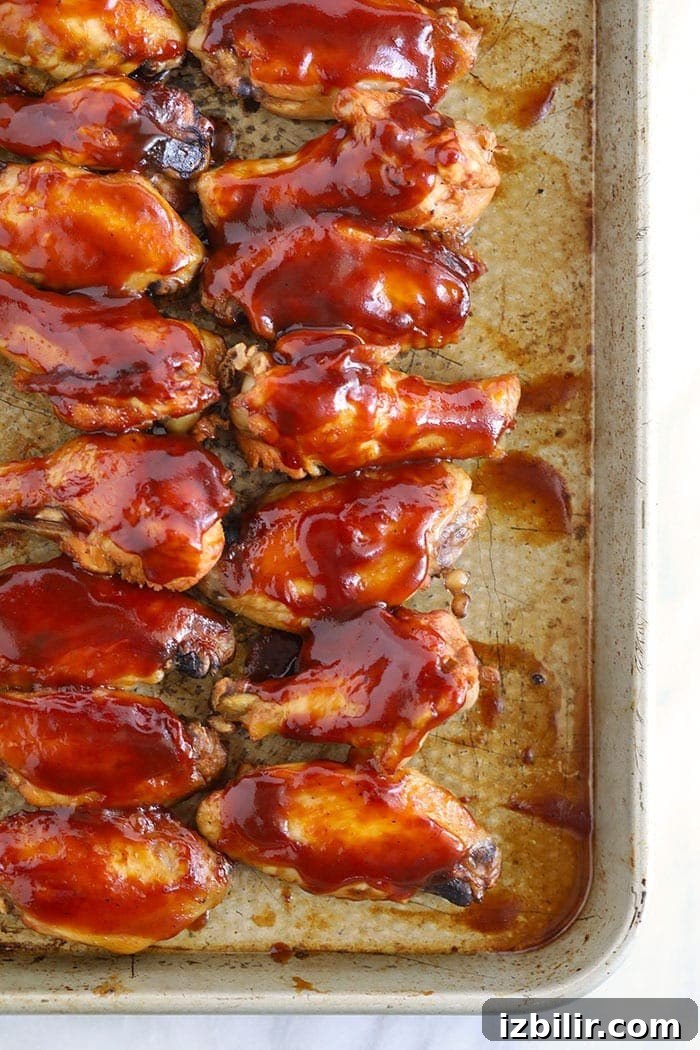 Crockpot wings glazed with BBQ sauce on a baking sheet bbq crockpot wings on baking sheet