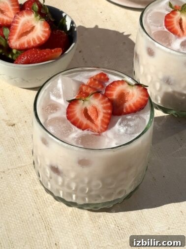 Creamy strawberry agua fresca in a glass with fresh strawberries
