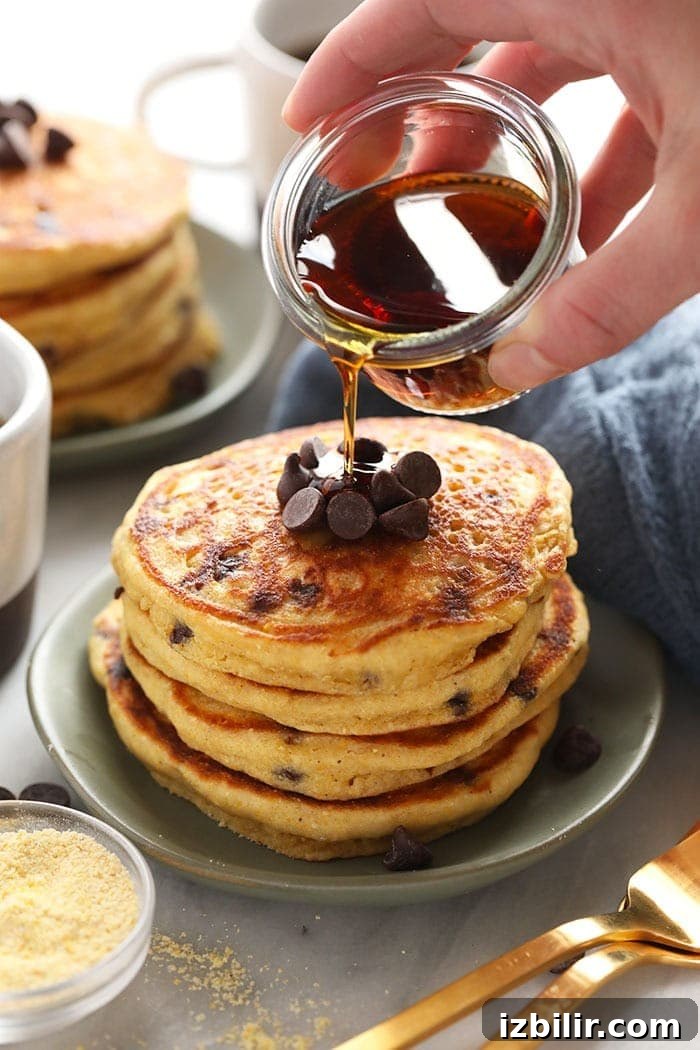 pouring maple syrup onto pancakes