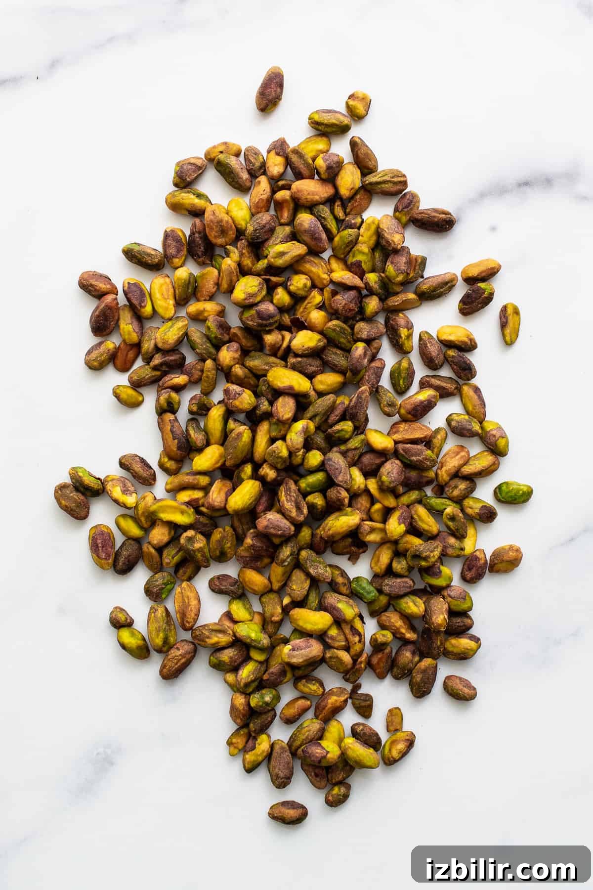 Homemade Maple Pistachio Butter with Sea Salt 3 Shelled pistachios on a counter.