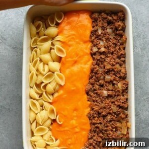 Ground Beef Casserole with Sweet Potato Cheese Sauce 2 A person holding a casserole dish with ingredients before mixing
