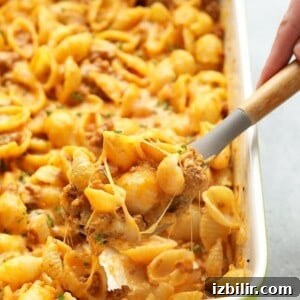 Ground Beef Casserole with Sweet Potato Cheese Sauce 3 A person scooping hamburger pasta out of a casserole dish