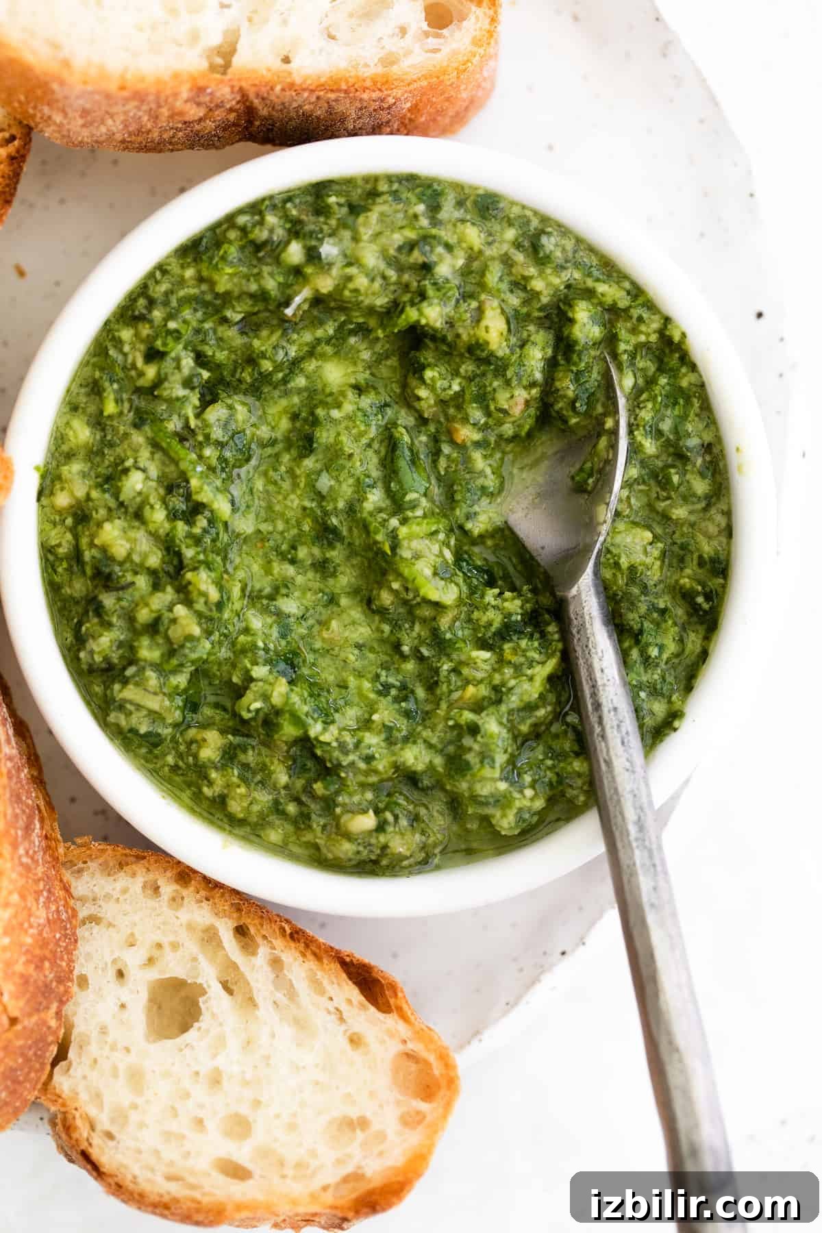 This basil pesto is made with simple ingredients of fresh basil, parmesan cheese, garlic, lemon juice, and olive oil. This pesto recipe is perfect for bread dipping and delicious tossed with pasta. pesto with spoon in bowl