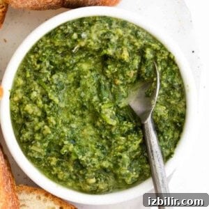 Homemade Basil Pesto Recipe with Pine Nuts and Parmesan 3 A bowl of homemade pesto with bread and a spoon.