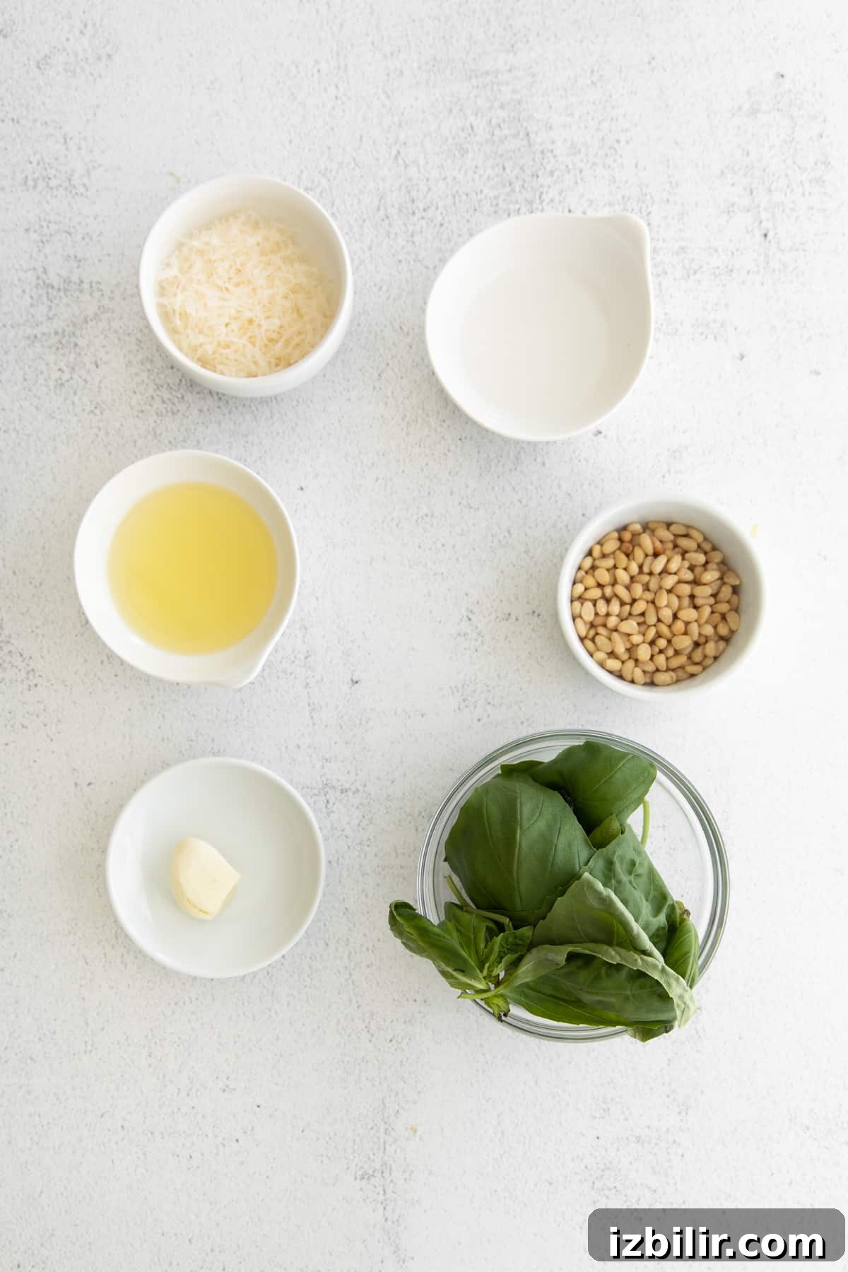 This basil pesto comes together quickly from fresh basil, garlic, olive oil, parmesan, and pine nuts. ingredients on countertop