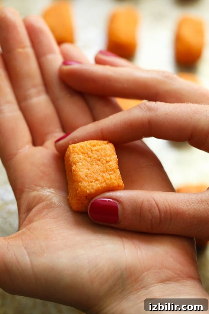 Form the sweet potato mixture into tater tots by hand A pair of hands forming a tater tot.