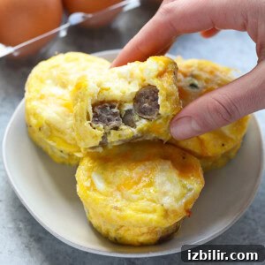 A person grabbing an egg muffin from a plate.