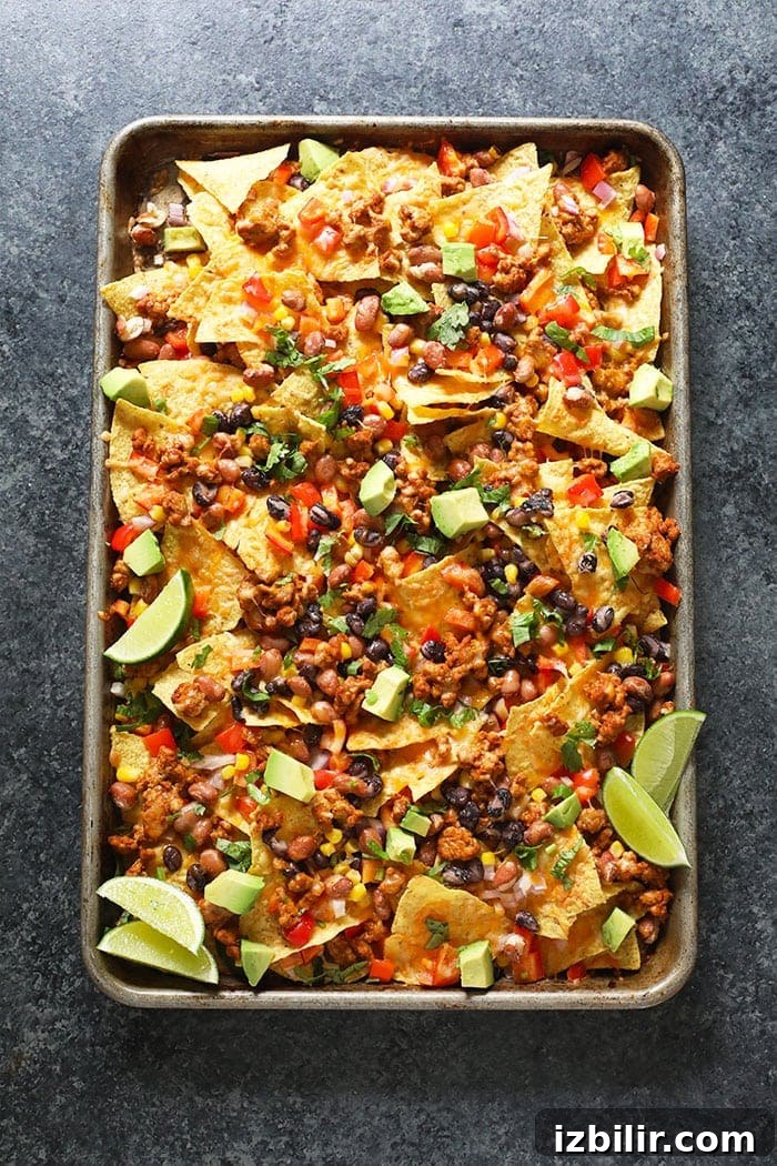 Baked chicken nachos on a baking sheet.