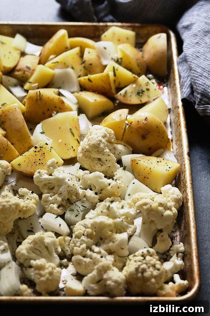 seasoned potatoes and cauliflower on a baking sheet