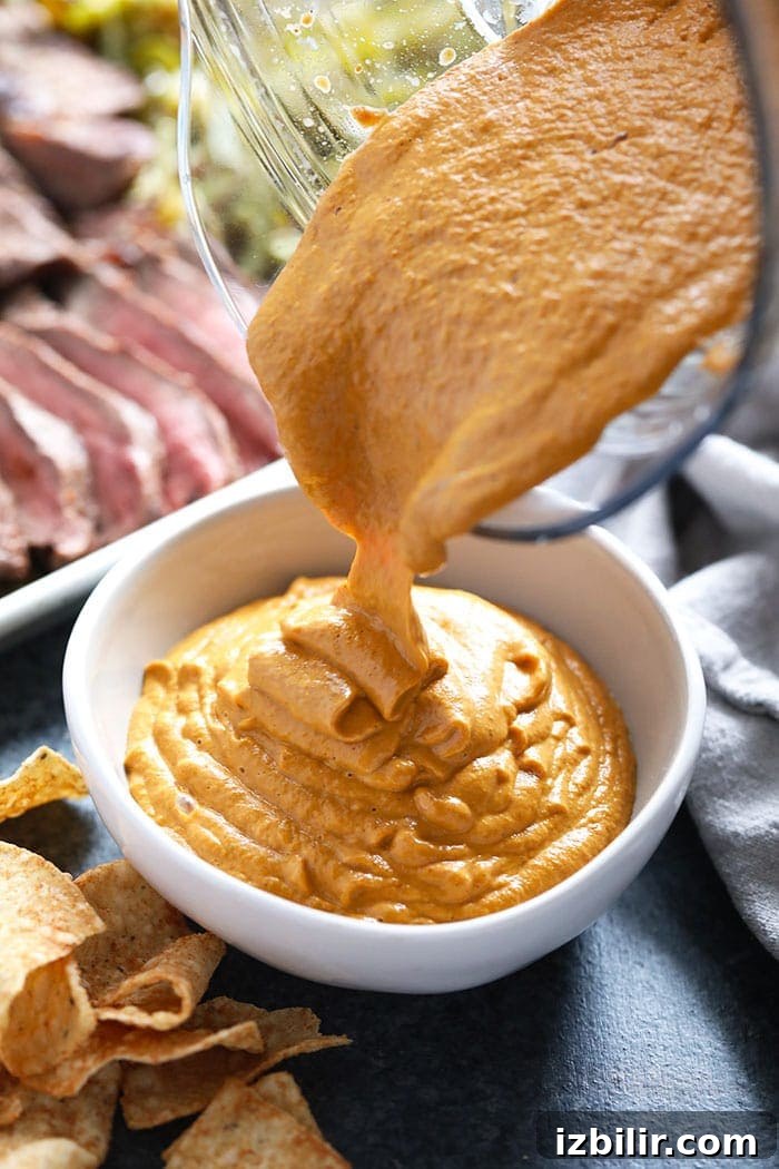 Creamy Vegan Queso Dip Recipe with Cashews 4 Vegan queso being poured in a bowl.