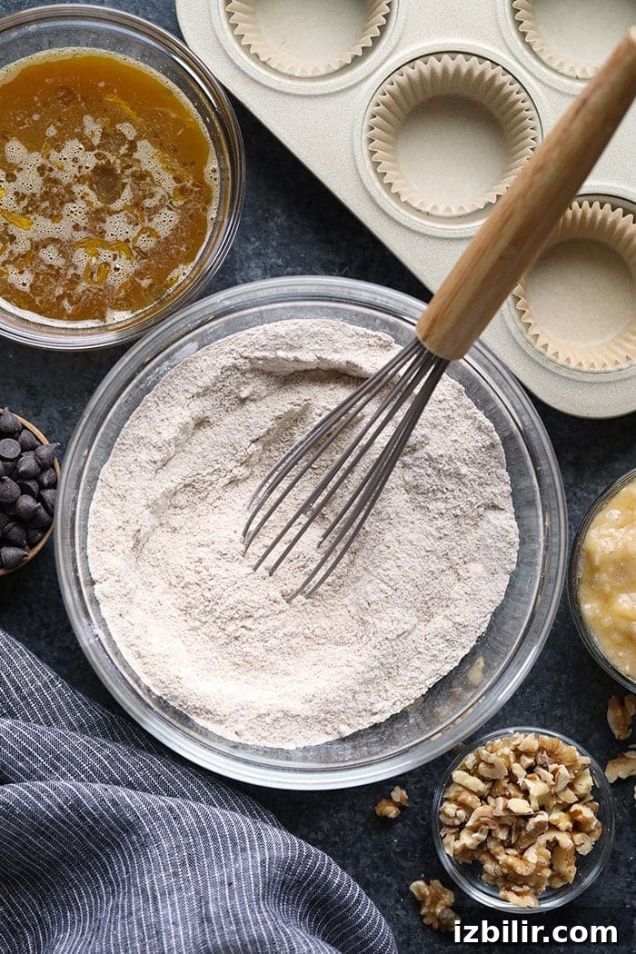Bowl with flour and whisk and muffin ingredients