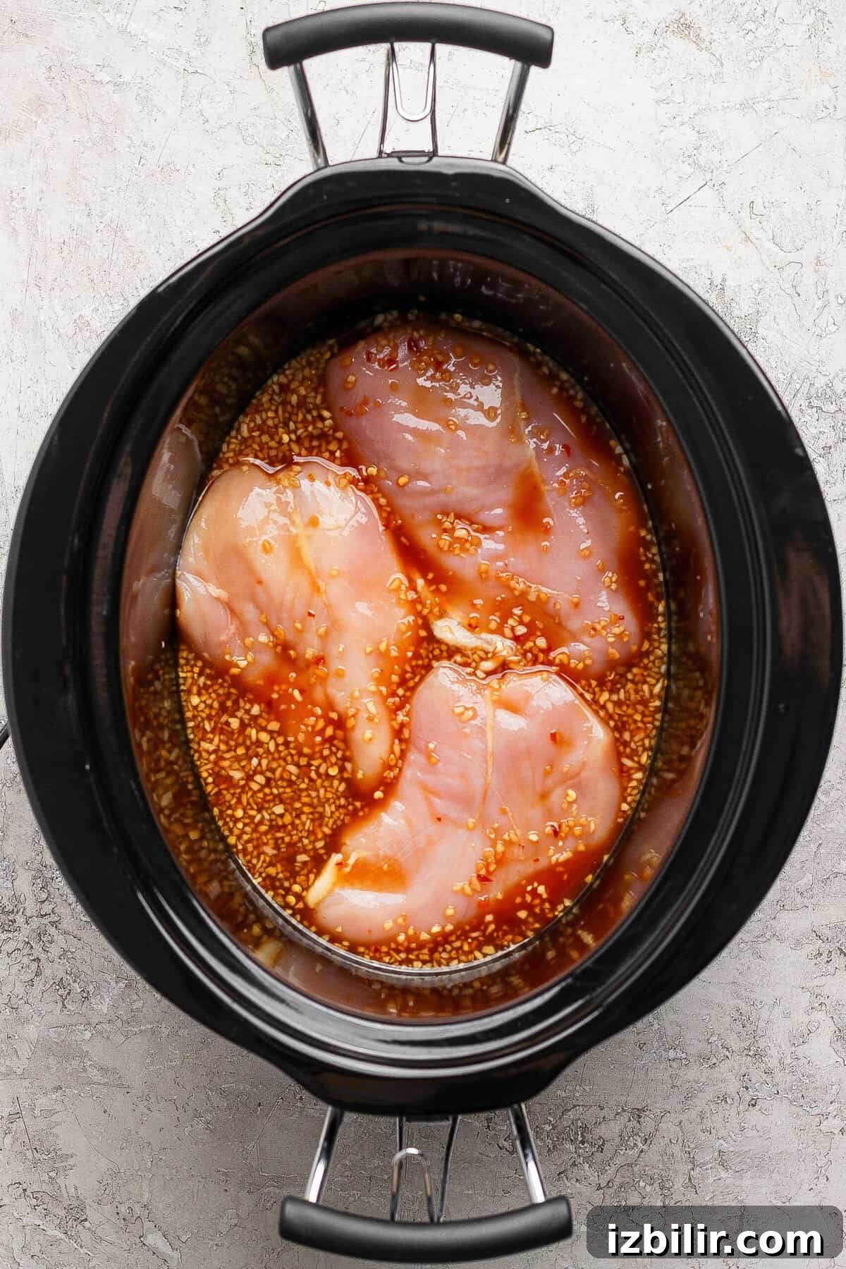 Sticky Honey Garlic Chicken Recipe 3 Raw chicken breasts in a crockpot with honey garlic sauce ready to cook