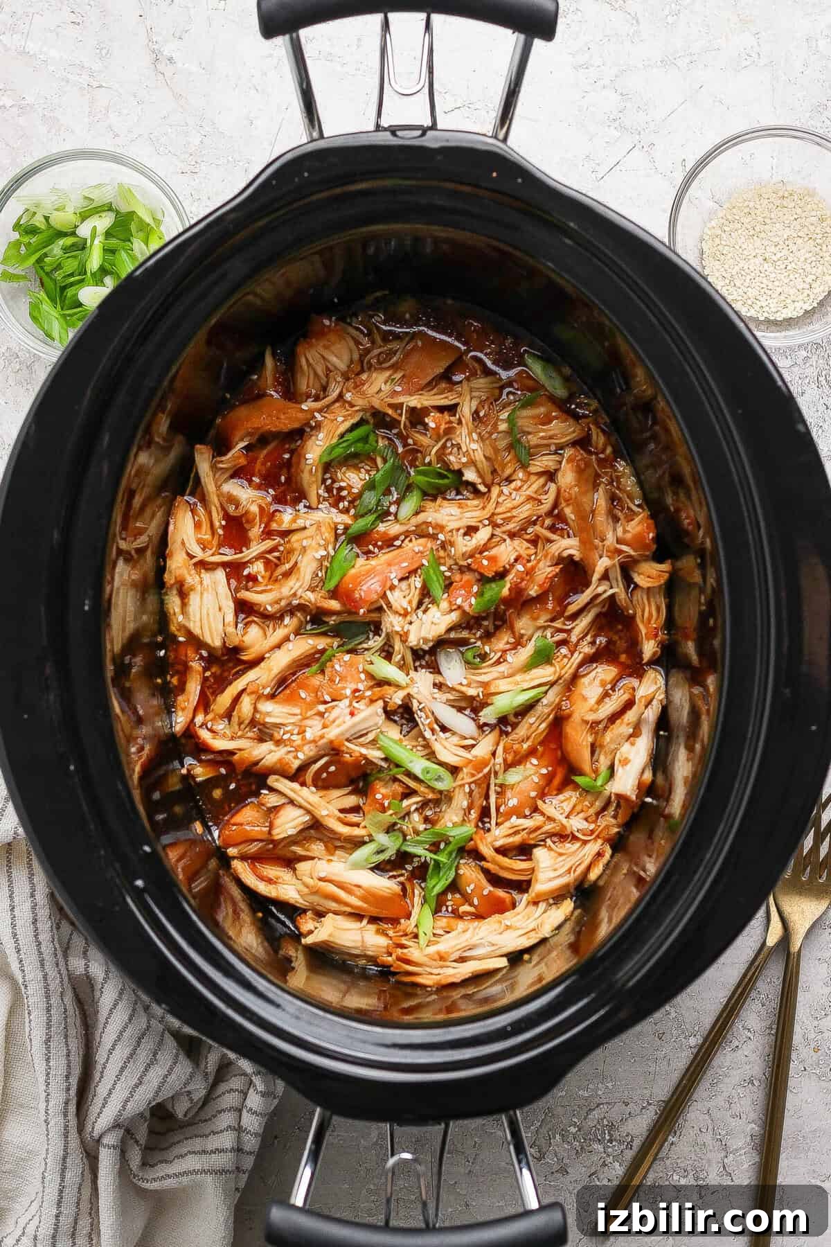 Sticky Honey Garlic Chicken Recipe 7 Shredded crockpot honey garlic chicken topped with green onions and sesame seeds in a slow cooker