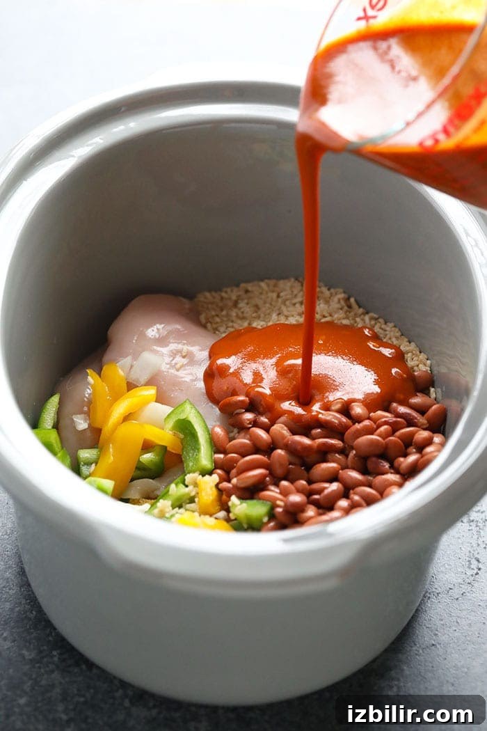 Pouring enchilada sauce into a slow cooker.